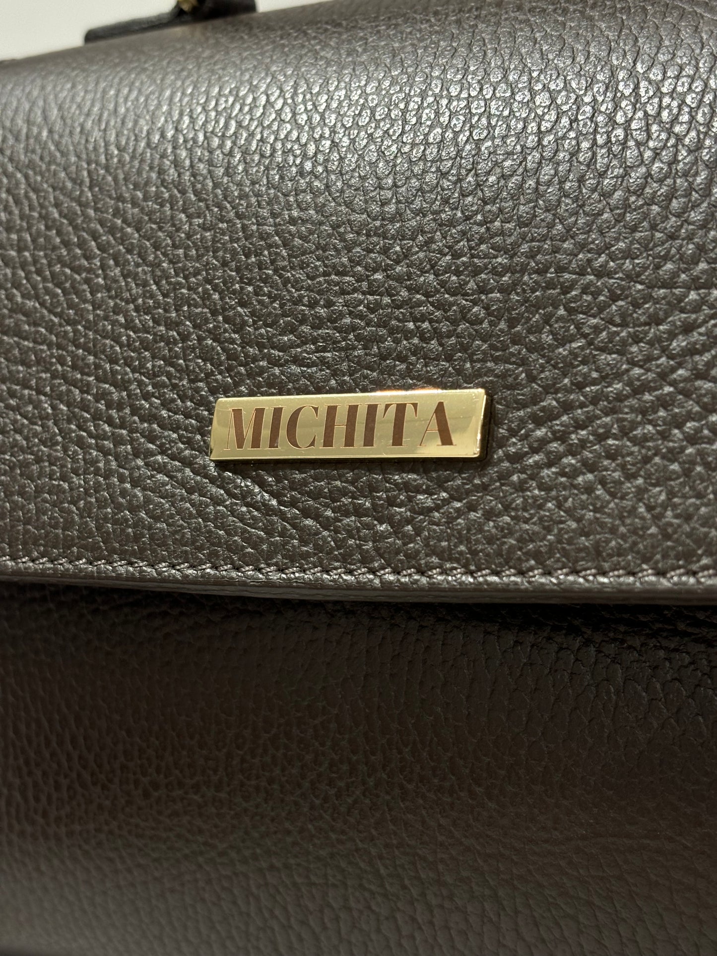 Dettaglio logo MICHITA in metallo dorato su Florence Bag in vera pelle Dark Chocolate