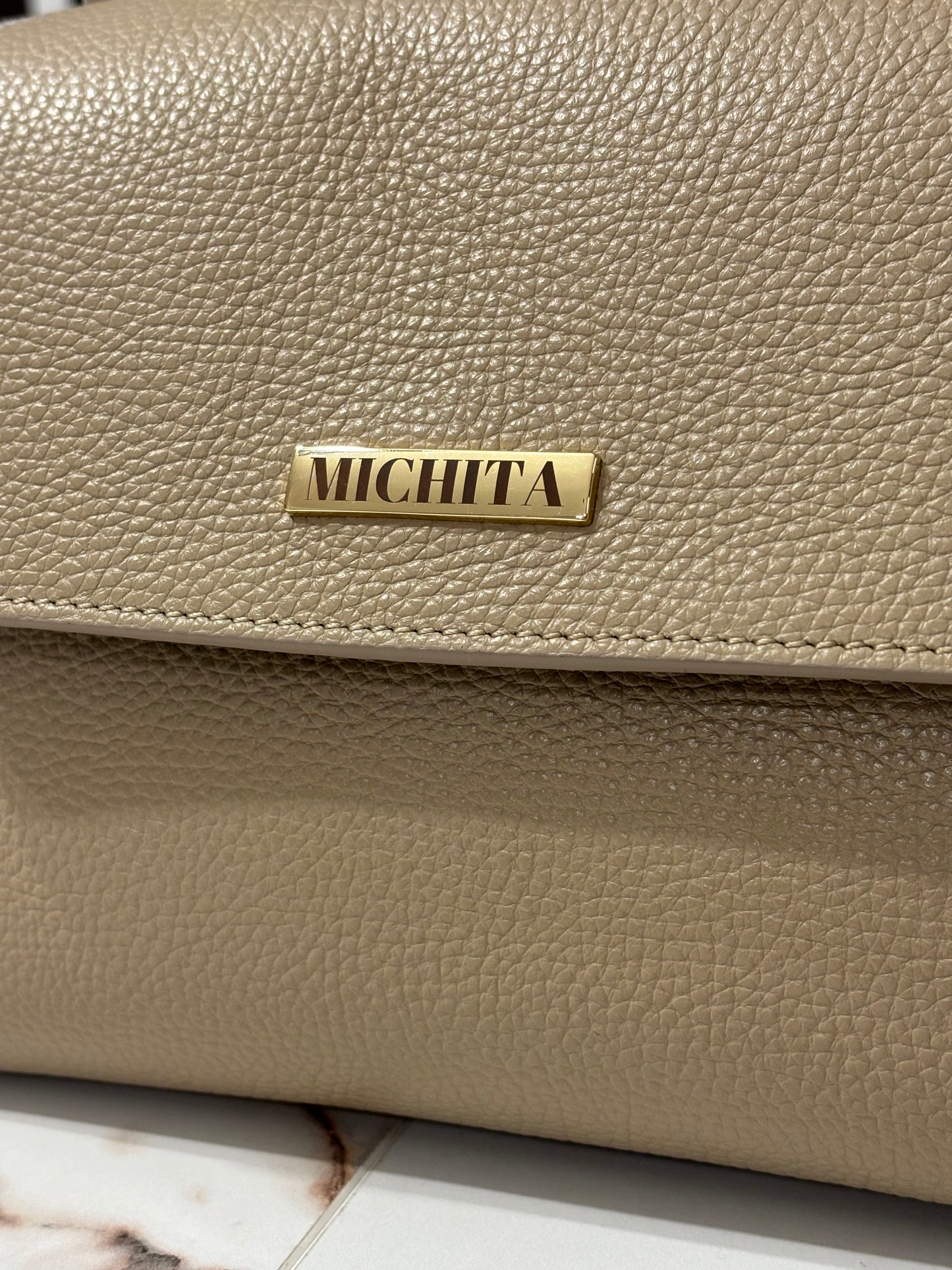 Dettaglio logo MICHITA in metallo dorato su Florence Bag in vera pelle Taupe